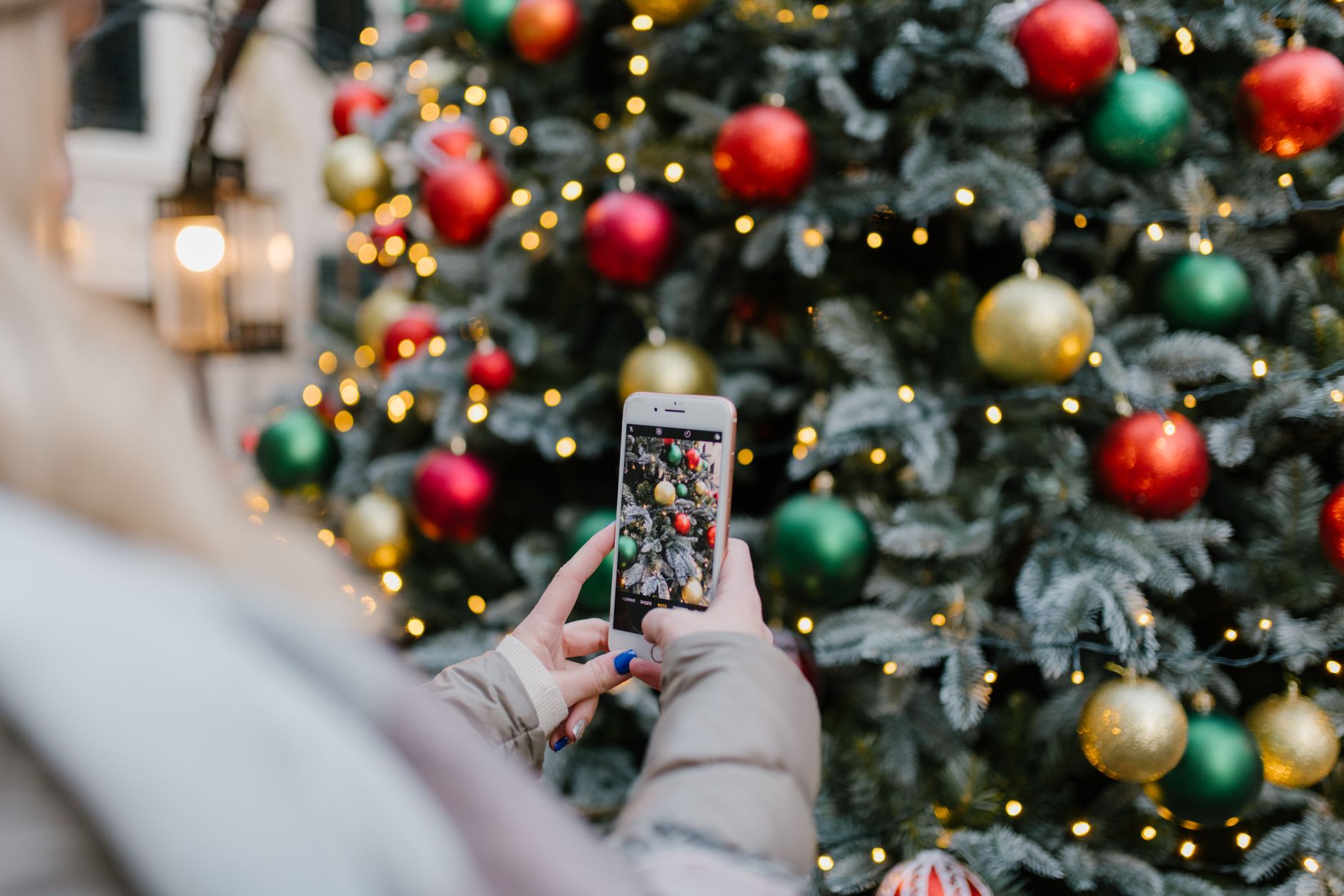 Family posing in front of a Christmas tree for a phone photo on a tripod