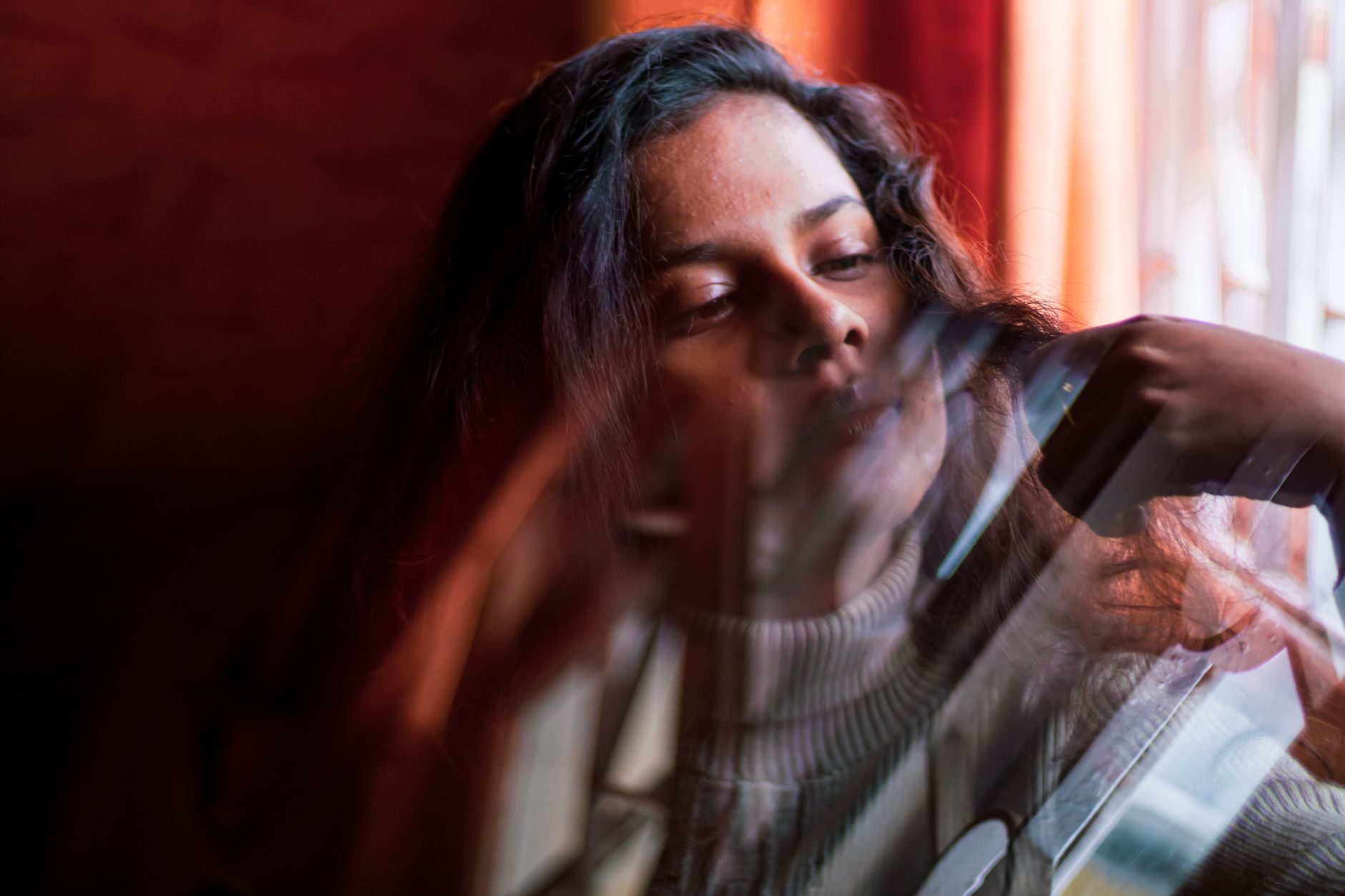 Woman sitting by a bright window, lit by soft midday daylight for a holiday portrait