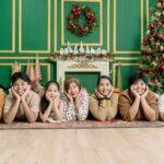 Family posing for a DIY Christmas card photo at home in front of the tree