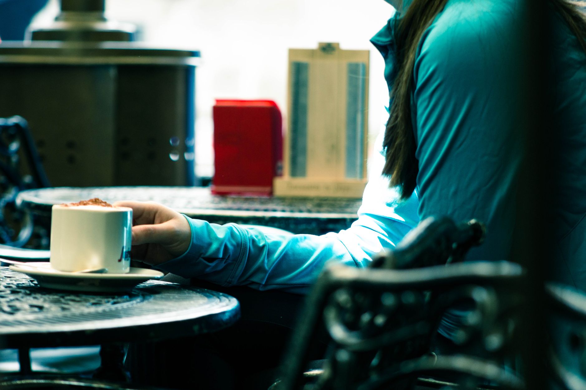 Woman enjoying a quiet morning coffee alone at a cafe while her partner sleeps in