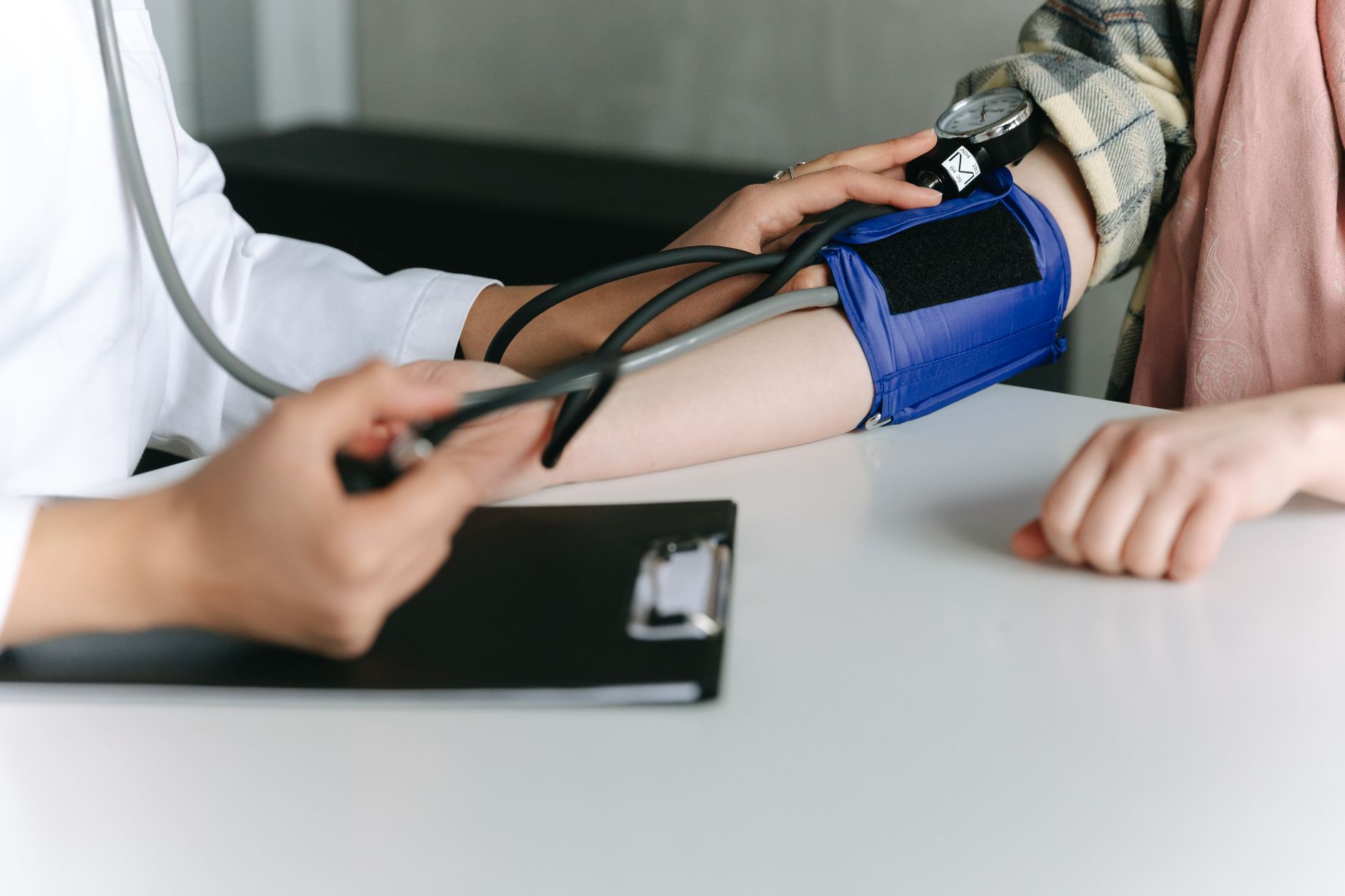 A healthcare worker uses a sphygmomanometer to check a patient's blood pressure in a medical office, illustrating Decide now what you'll say if something feels wrong