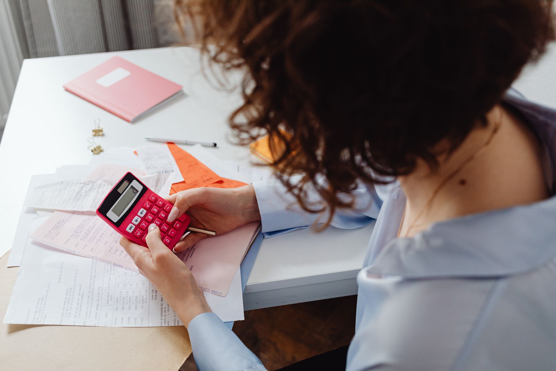 Woman planning her wedding season budget in a notebook with a calculator