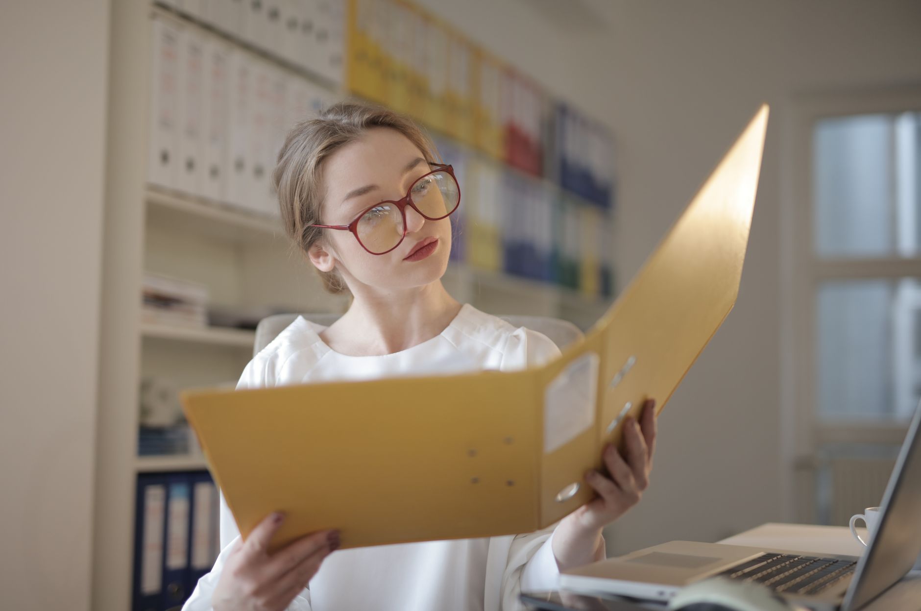 Caucasian woman intensely reading documents in an office setting, illustrating Build Your Case: Document Your Accomplishments