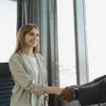 Woman smiling and shaking hands at a business office, signaling a successful job interview, illustrating How to Negotiate Your Salary: A Step-by-Step Guide for Women