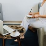 Woman in home setting taking notes with laptop and coffee on table, illustrating How to Start a Side Hustle: 12 Profitable Ideas for Women with Full-Time Jobs