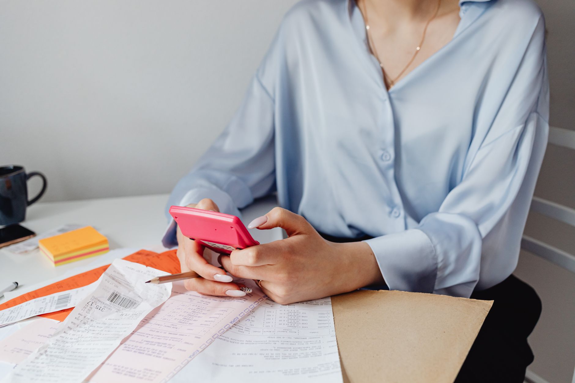 Woman checking salary numbers on a calculator at her desk