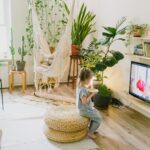Child enjoying a snack in a cozy living room with lush plants and a hammock chair, illustrating Interior Design on a Budget: Transform Your Home Without Breaking the Bank