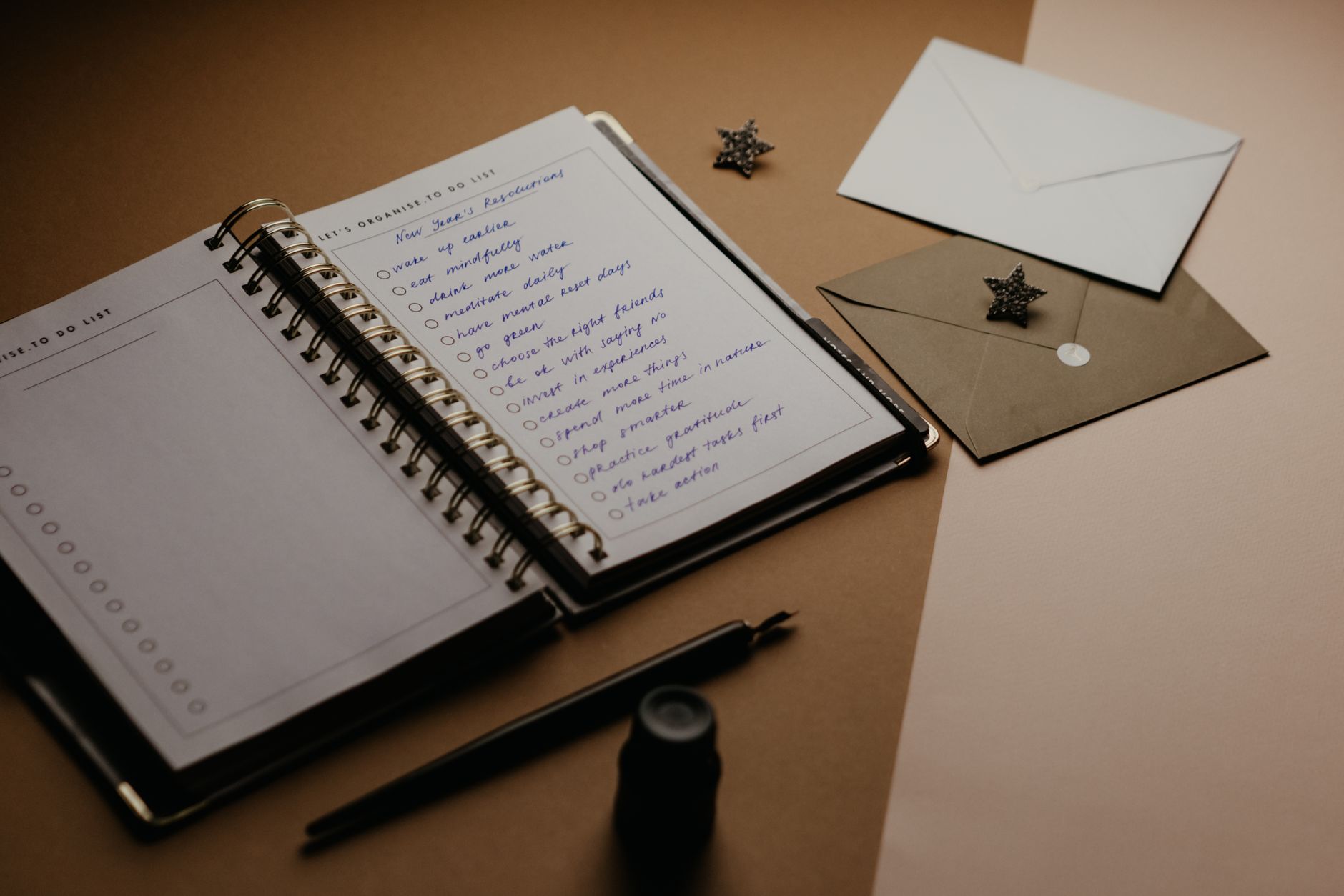 A tidy desk setup featuring a planner, to-do list, envelopes, and a pen, illustrating Prioritizing Tasks and Setting Goals
