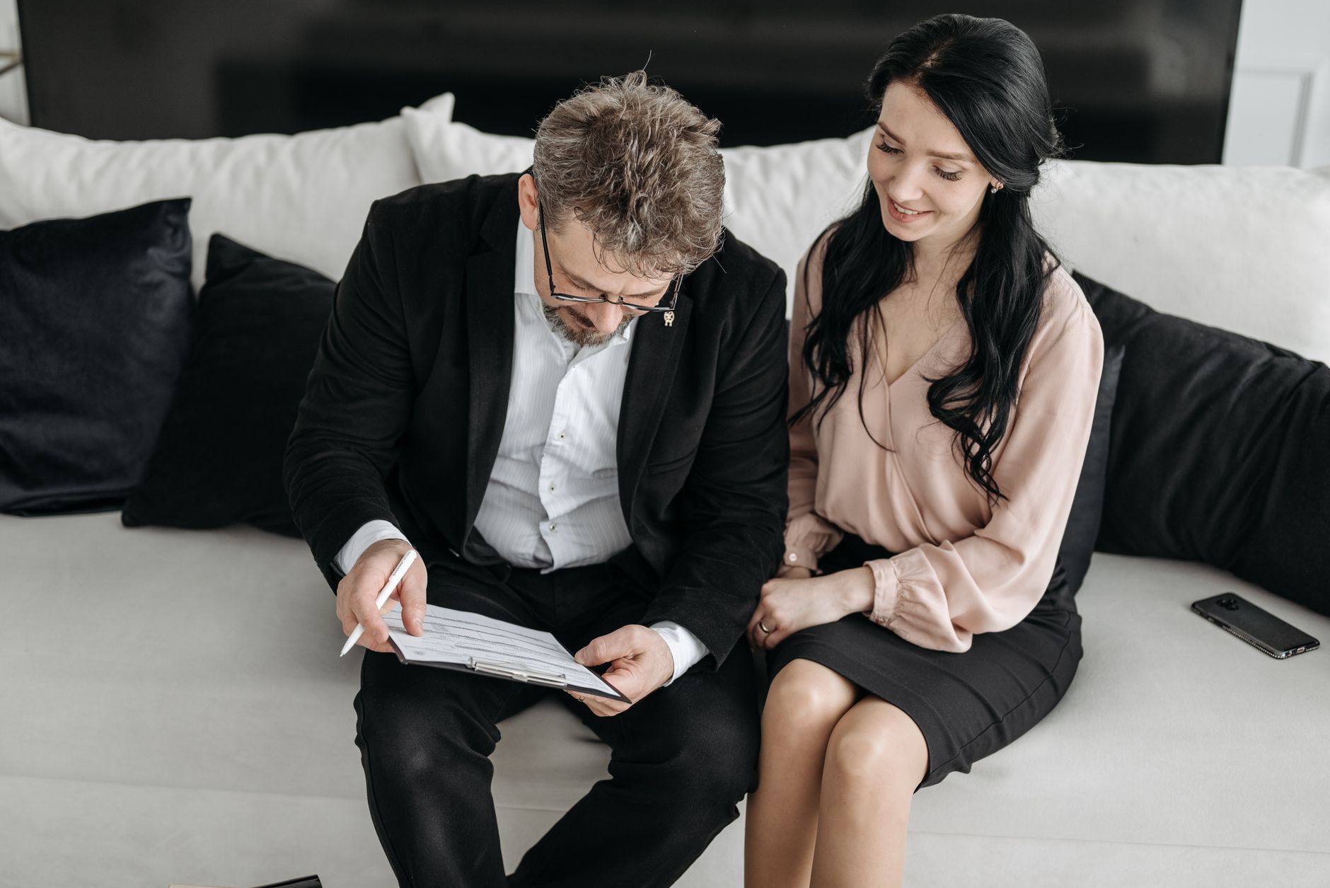 Couple reading a lease agreement together at a kitchen table before moving in together
