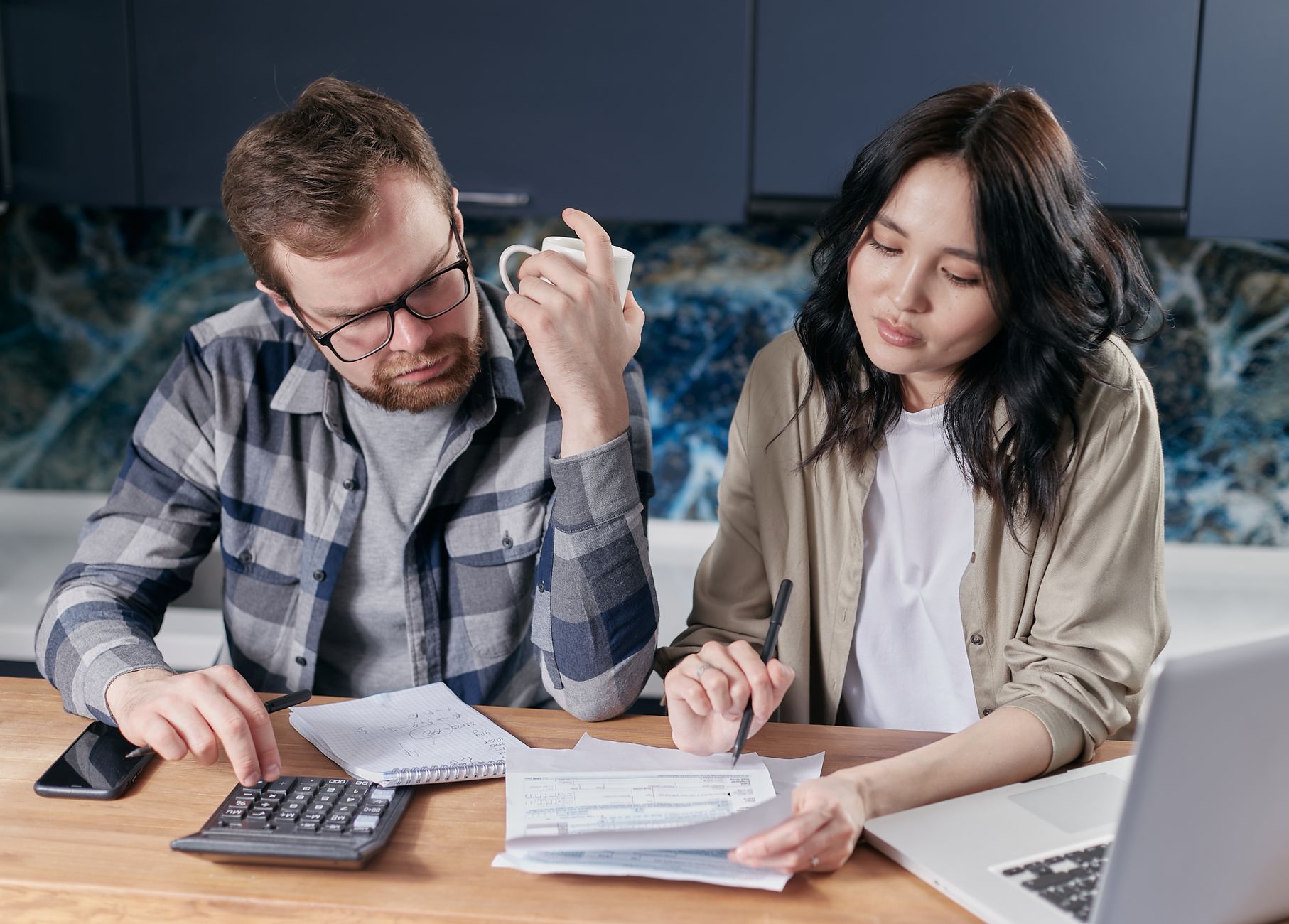 Couple working out a proportional rent split with a calculator and notebook