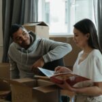 Couple carrying moving boxes into their first shared apartment