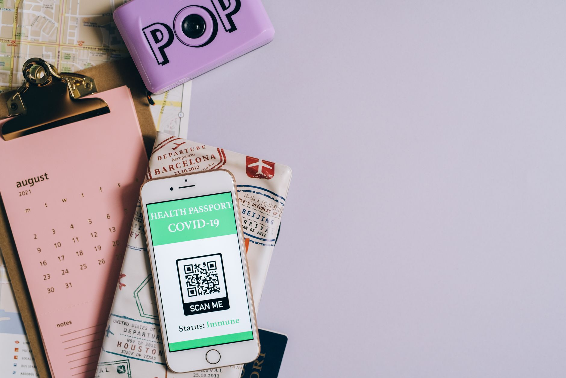 Flat lay image of a health passport with a COVID-19 QR code, calendar, and map, illustrating Passport processing times are reasonable right now, and that won't last