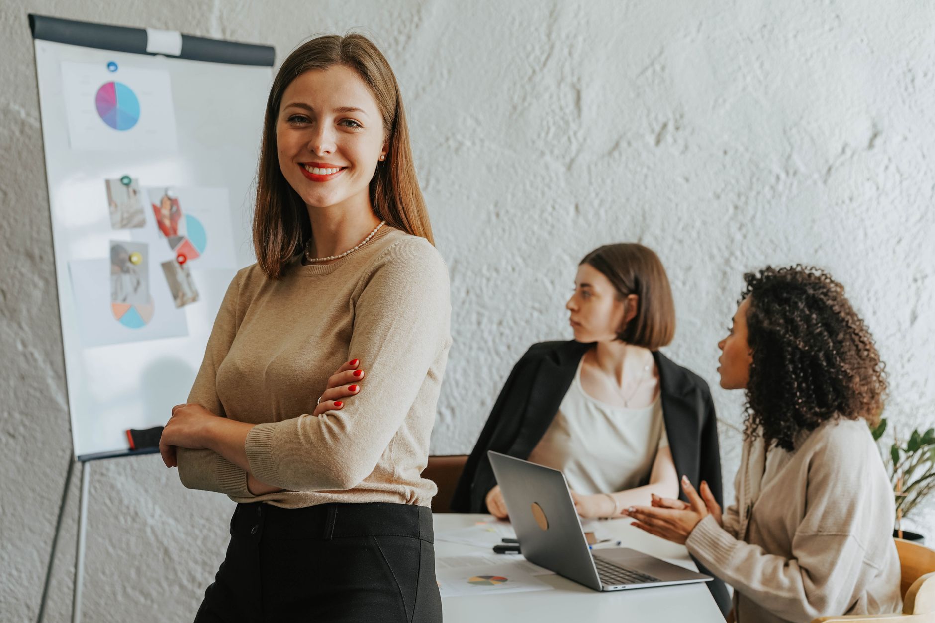 Confident woman smiling in a modern office setting with colleagues at work, illustrating Negotiating Your Worth