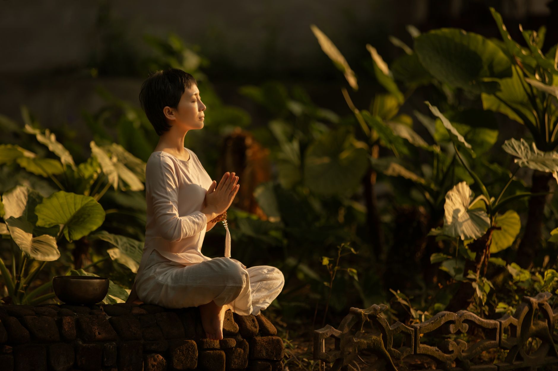 Serene scene of a woman meditating in a lush garden setting at daylight, illustrating Prioritize Self-Care and Mindfulness