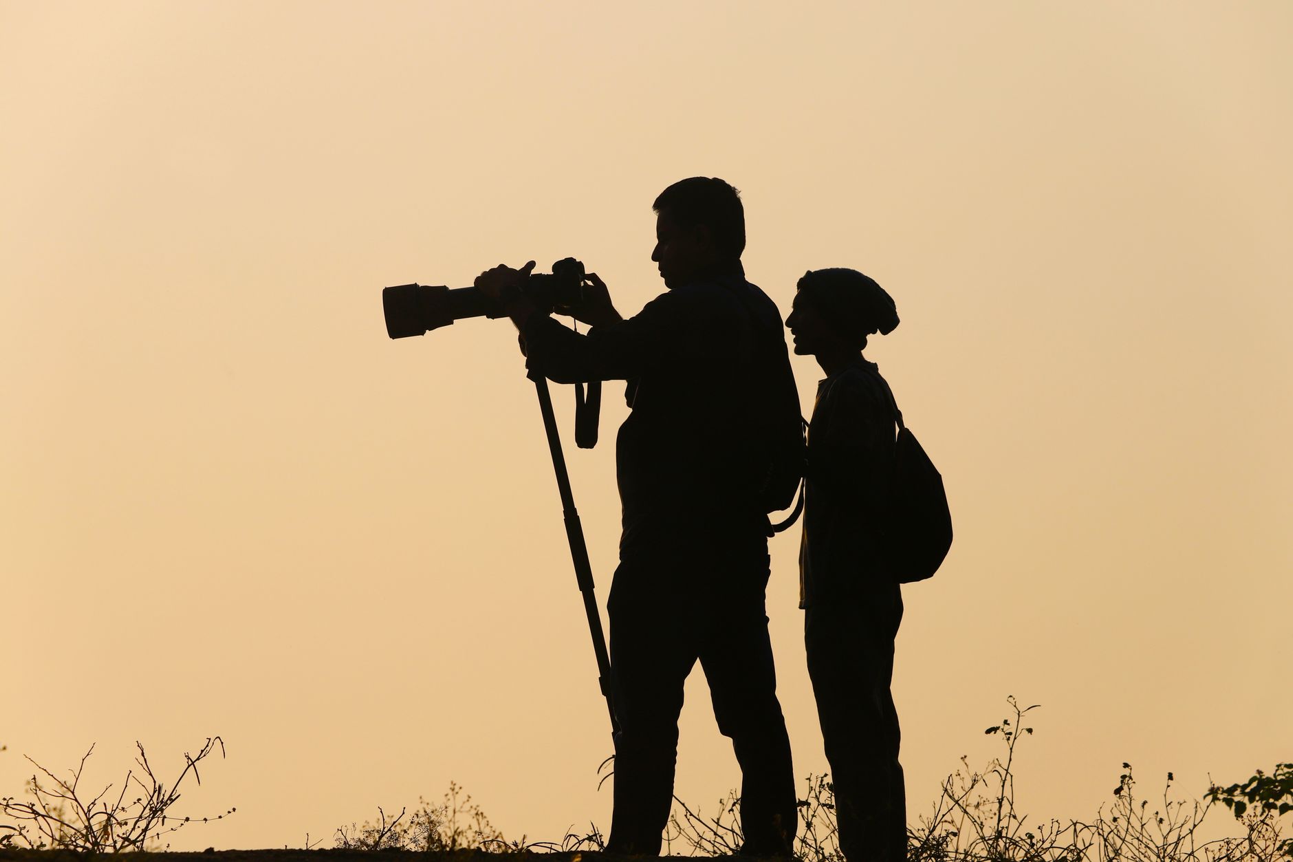 Two photographers silhouette with cameras during sunset, capturing serene landscapes, illustrating Photo Composition Rules That Actually Make Sense