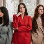 Three women in blazers posing with confidence, exuding modern fashion and style indoors, illustrating The Working Woman's Guide to Building a Professional Wardrobe