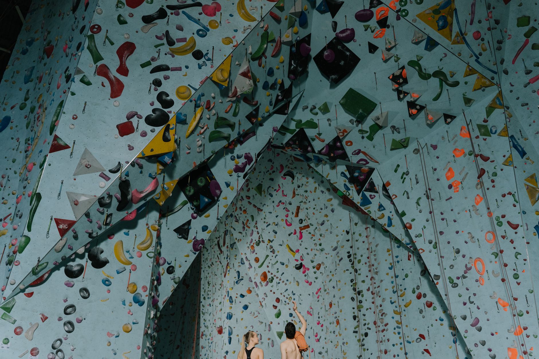 Two people climbing a vibrant indoor bouldering wall with varied holds, illustrating The research on Valentine's Day date ideas favors novelty over nice