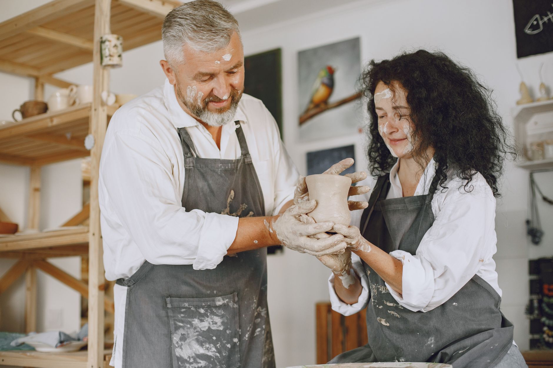A couple working together on crafting a clay pot in an indoor art studio, illustrating A novel date is usually cheaper than a fancy dinner