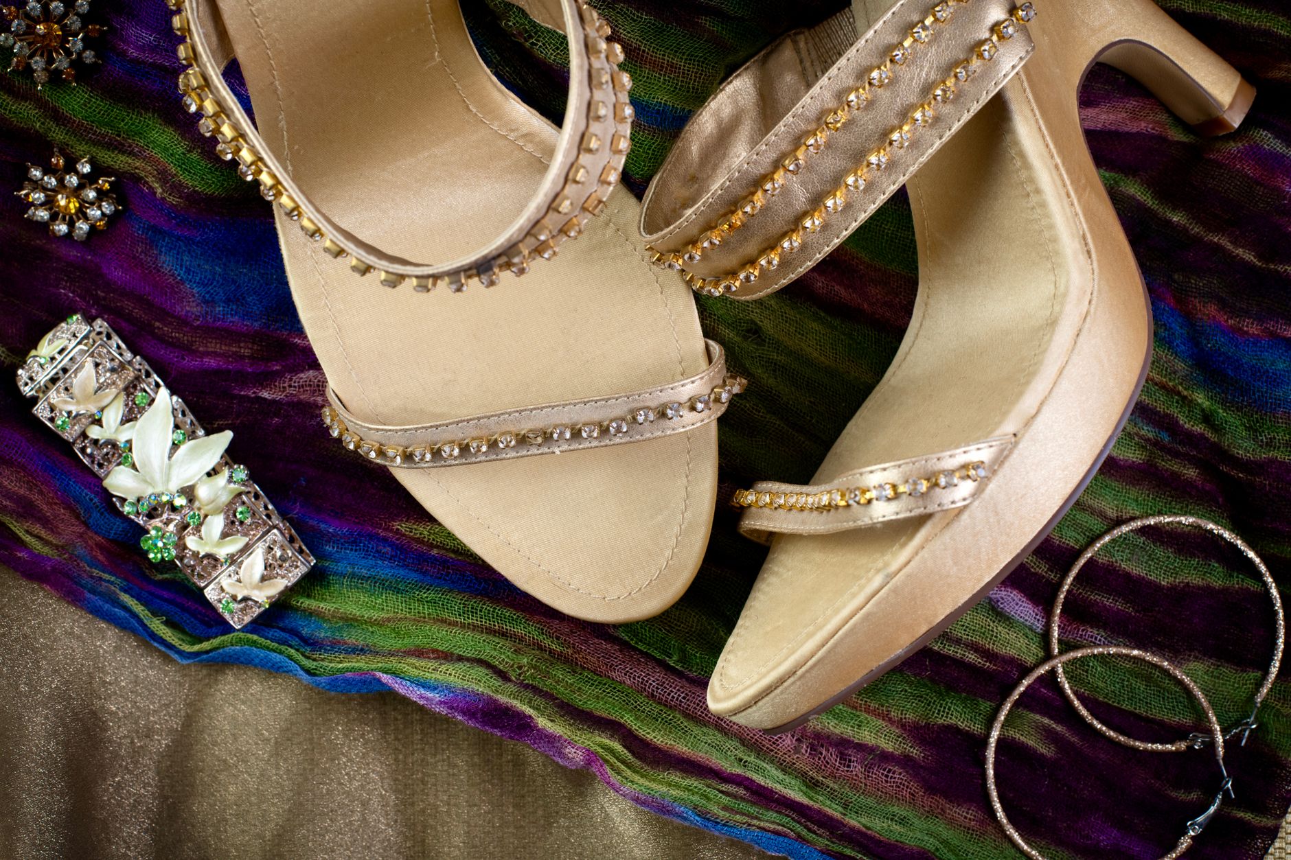 Showcase of bejeweled sandals and accessories on a vibrant scarf. Perfect for fashion and elegance, illustrating How to pick the one wedding guest dress you'll rewear