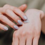 Crop unrecognizable female in casual shirt with trendy manicure and ring rubbing hand cream in back of hand skin, illustrating Winter Dry Skin Is a Room Problem: Check This $10 Number Before You Buy Another Cream